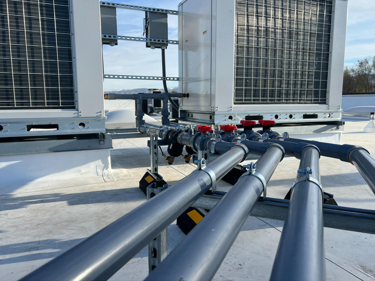 Close-up of rooftop piping system with red shutoff valves