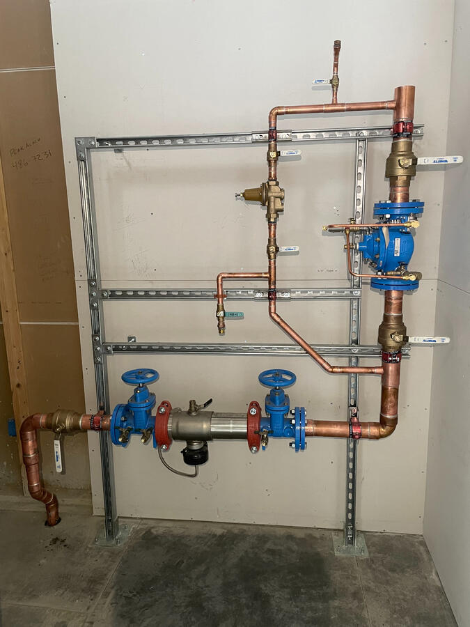 Wall-mounted copper piping system with backflow preventers and shutoff valves