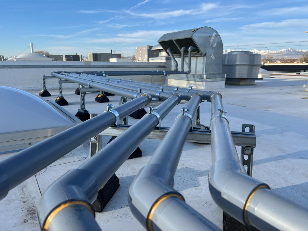 Rooftop mechanical piping installation with blue sky background