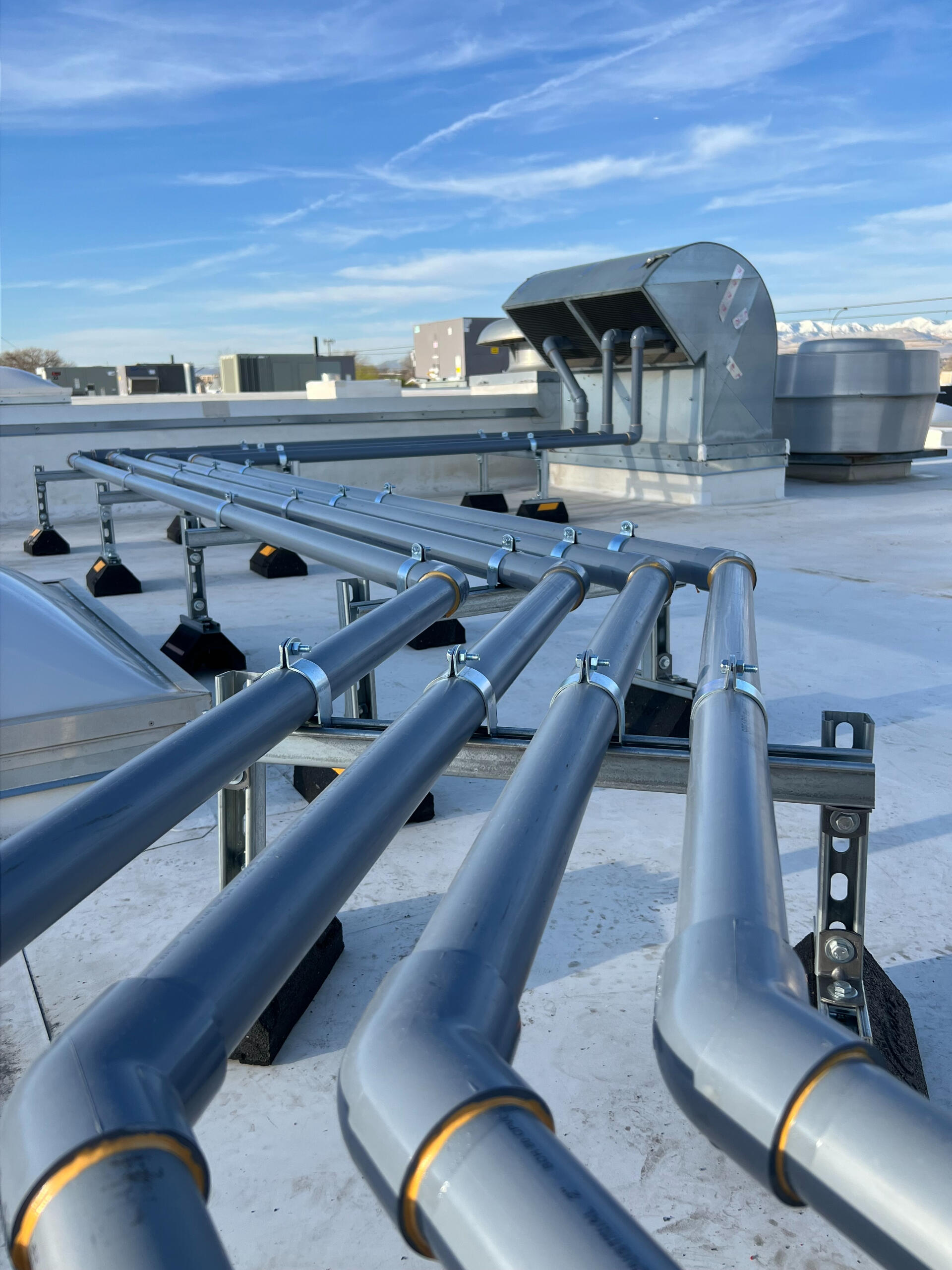 Industrial rooftop piping installation completed by Deseret Peak Piping under a clear blue sky
