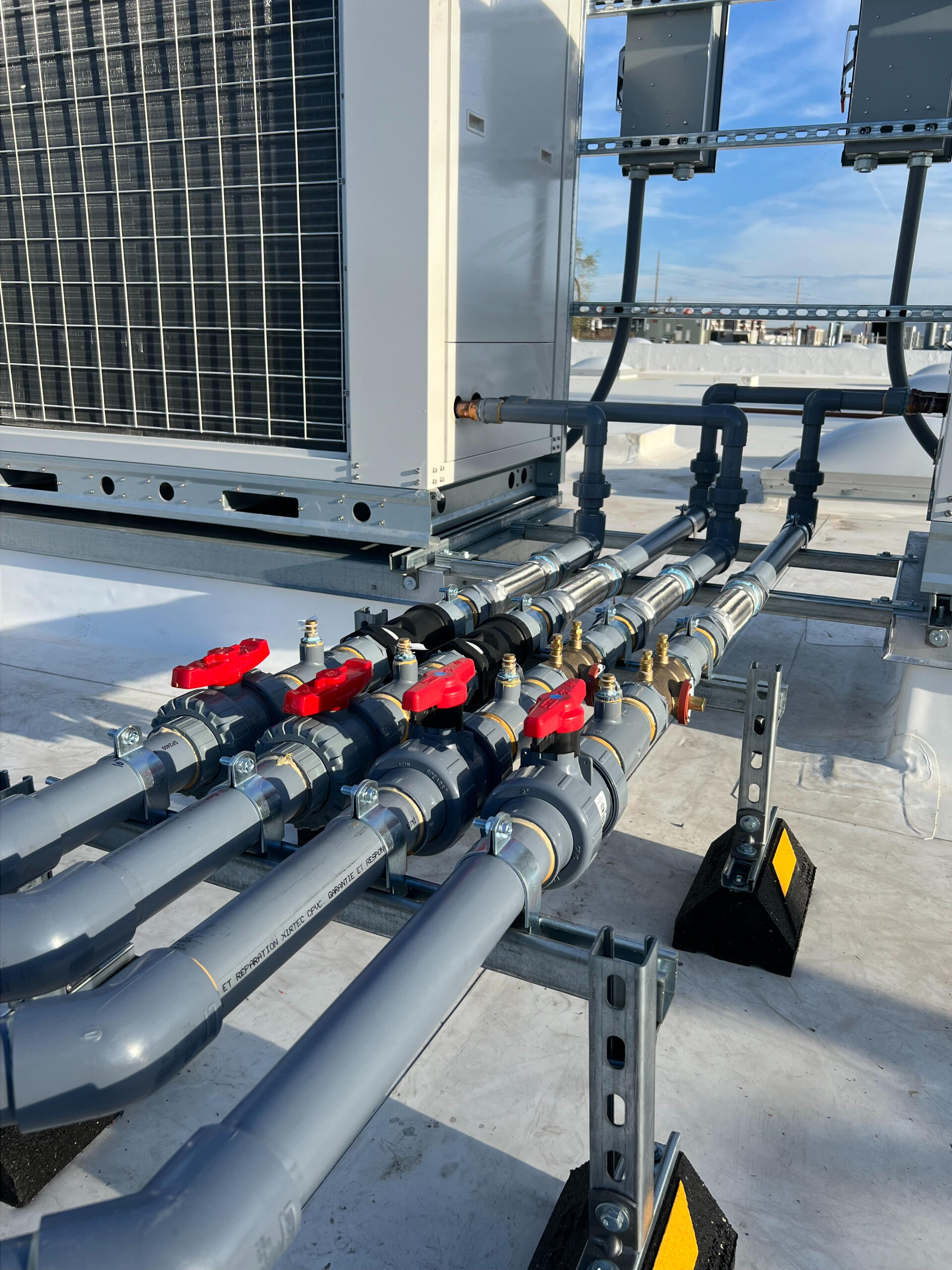 Rooftop piping system with red shutoff valves maintained by Deseret Peak Piping